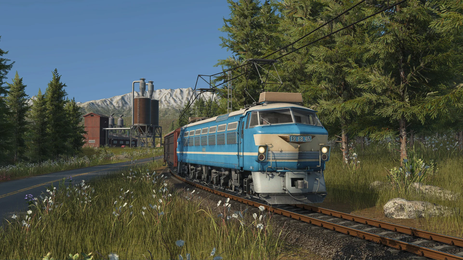 A blue locomotive travels through a forest in Transport Fever 3